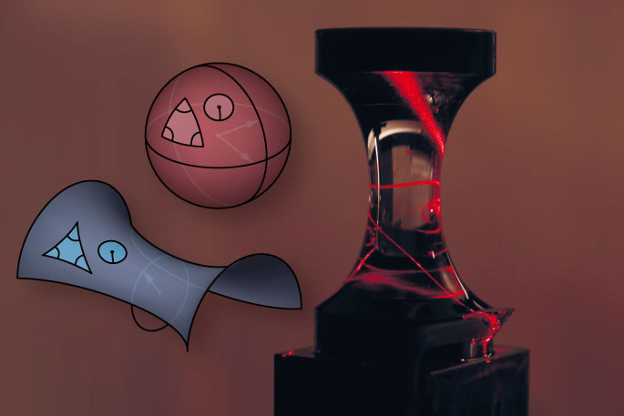 Die Abbildung zeigt, wie sich ein Laserstrahl im Experiment entlang der zweidimensionalen Oberfläche einer sanduhrförmigen Glasfigur ausbreitet und sich dabei einmal um die Figurentaille windet. Diese Figur ist ein Beispiel für eine negativ gekrümmte Oberfläche (vergleiche z.B. mit einem Sattel), im Gegensatz zu einer positiv gekrümmten Oberfläche, wie die einer Kugel. (Bild: Vincent Schultheiß)