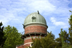 Das Bild zeigt die Sternwarte Bamberg mit ihrem kuppelförmigen Dach inmitten von Bäumen.