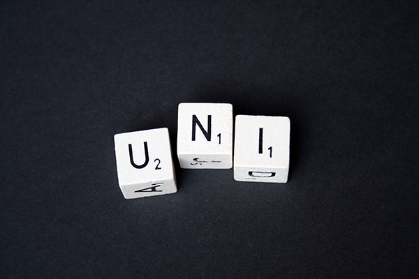 Das Foto zeigt drei Würfel. Auf den Würfeln steht jeweils ein Buchstabe, woraus sich das Wort "Uni" ergibt.