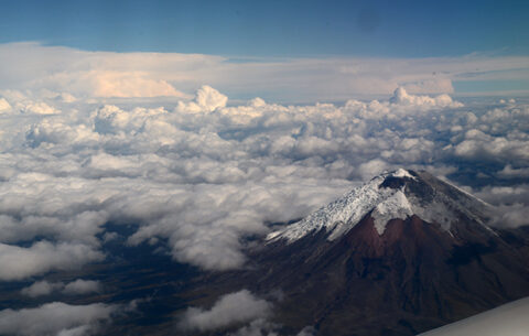 Das Foto zeigt den zweithöchsten Berg Ecuadors, den Cotopaxi. Er ist von Wolken eingehüllt. Auf der Spitze des Vulkans sieht man Schnee.